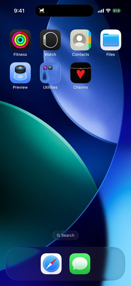 The top of a phone home screen, with a small cat charm sitting in the Dynamic Island